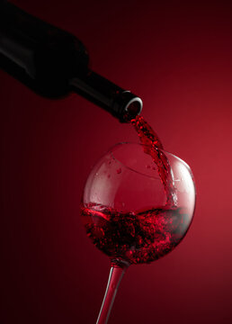 Pouring red wine from a bottle into a glass.
