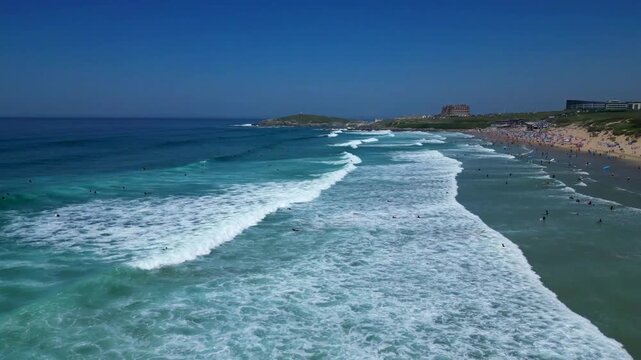 Newquay, North Cornwall, England: DRONE VIEWS: A low angle of surfers in the sea waiting for incoming waves off Fistral Beach. Fistral bay is a venue for major international surfing competitions.