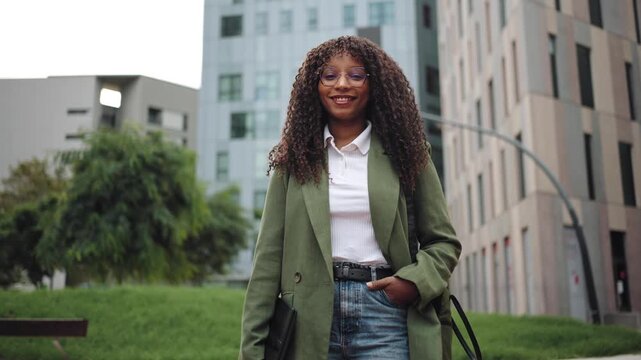 Portrait of Young African American business woman with green blazer smiling in a modern corporate city
