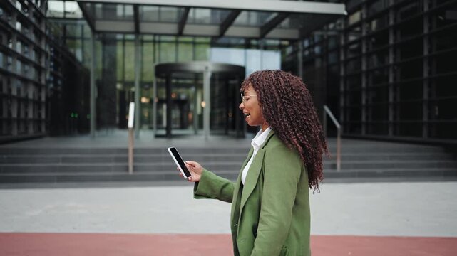 Young Businesswoman Walking In Modern City Making mobile Phone video Call using EarPods