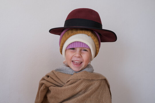  girl wrapped in warm scarf wearing several knitted winter beanies