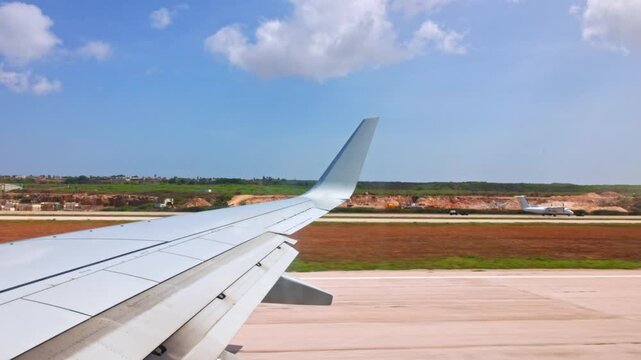 Close-up view of airplane wing during landing on runway at tropical airport in Curacao.