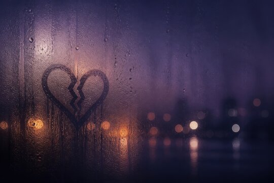 Broken heart drawing on foggy window with city lights