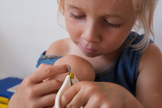Focused little girl carefully trimming nails with scissors at home