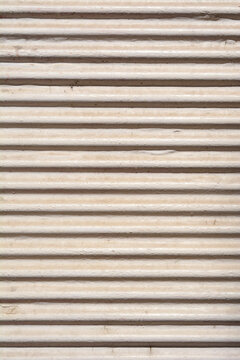 A close up background view of a weathered white corrugated metal shutter showing tight horizontal parallel lines with dirt particles