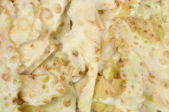 Full frame background texture of freshly cut fibrous white and green peelings from raw celeriac root.