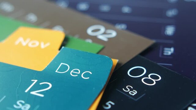 Macro close up of colorful paper calendar tabs showing november and december with dates and days of the week