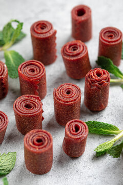 Healthy homemade berry fruit leather rolls pastila served with fresh mint leaves on grey table closeup
