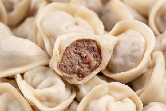 Close-up of boiled pelmeni dumplings showing juicy beef minced meat filling inside thin dough