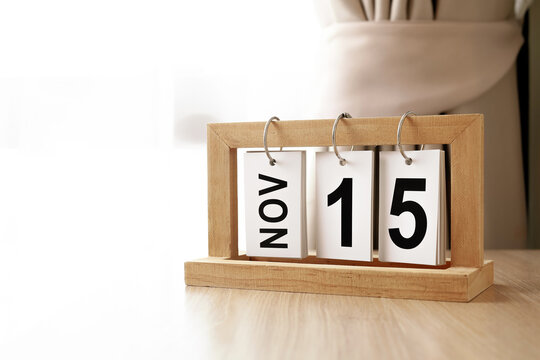 Wooden flip calendar showing November 15 on a wooden desk with copy space. Modern minimalistic home decor and date concept.