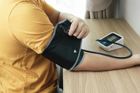 Man measuring his own blood pressure with digital monitor at home. Health checkup and healthcare concept.