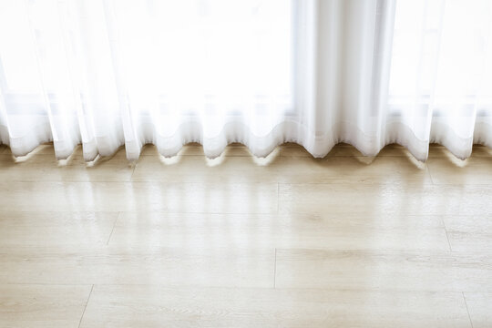 White sheer curtains near wooden floor with soft sunlight and copy space. Modern bright living room interior design concept.