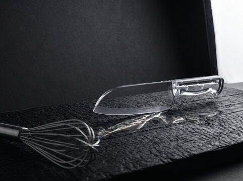 Kitchen knife and whisk on black stone kitchen counter surface