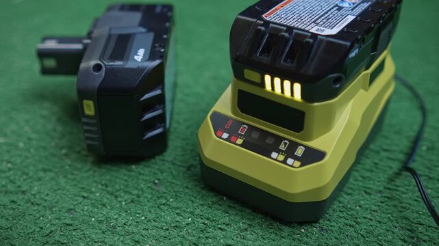 Power tool battery charging with level indicator lights and spare battery nearby showing charging process and energy status on working surface