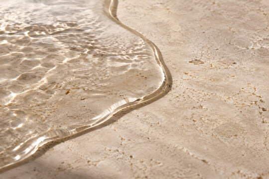 Glassy water meniscus on a pale stone surface