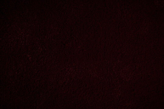 Close-up of painted, plastered and rough wall in dark red. Grungy high resolution full frame textured background. Front view, copy space.