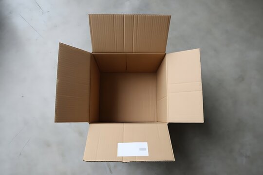 Open empty brown cardboard box sitting on a grey concrete floor surface