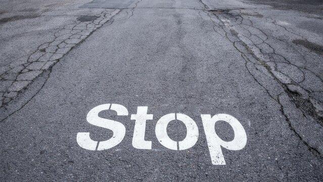 Stop sign painted on cracked asphalt road