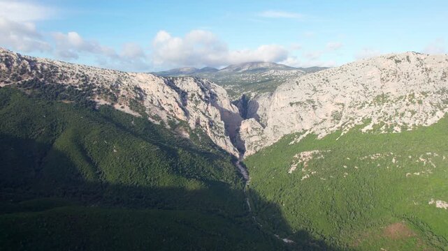 Drone view flying towards the Gorropu Gorge canyon , nestled between the imposing rocky mountains of the Supramonte range in Sardinia