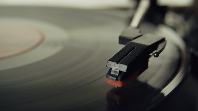 A turntable needle moves across a spinning vinyl disc in an extreme close-up shot. The scene highlights the texture of the record, classic audio equipment, and the experience of listening to music.
