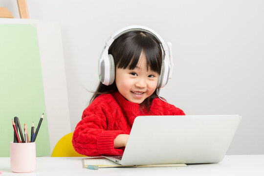 asian little girl studying online with laptop and headset, interactive e-learning concept