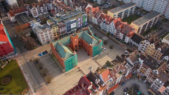 Kołobrzeg&rsquo;s city center from above, featuring the Town Hall under renovation, and the vibrant market square at sunrise.