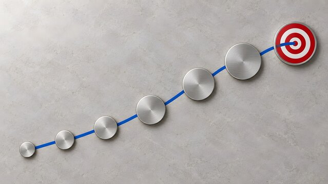 Strategic business roadmap concept showing metallic steps connected by a blue line leading upward to a red bullseye target on a textured concrete background.