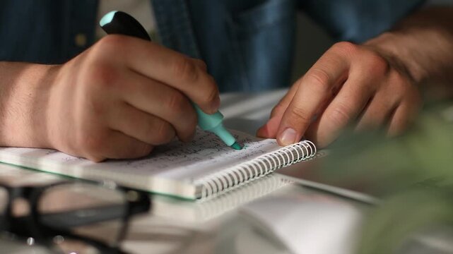 Close up of man highlighting handwritten notes in notebook