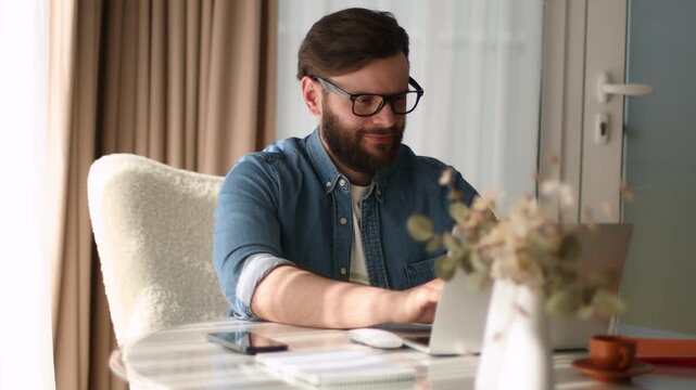 Man working on laptop and using mouse in bright home office