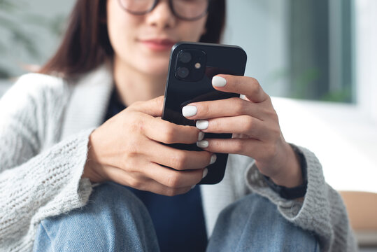 Close-up, young woman sitting on the floor at home interior, using smartphone for social network or online shopping via mobile app, modern people lifestyle concept