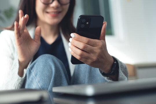 Remote work from home office. Young woman in casual wear using mobile phone for video call, chatting with colleague via mobile app, telecommuting, business casual