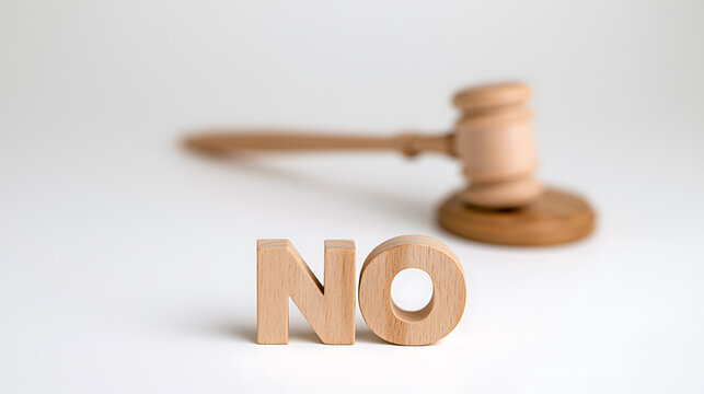 Wooden gavel placed behind wooden block letters spelling out the word no on a clean white background representing legal refusal or ban