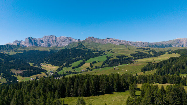 View of beautiful landscape in the Alps with fresh green meadows in the background on a sunny day with blue sky and clouds in summertime. Alpe de Siusi, Dolomite Alps