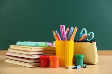 Different stationery on wooden table near chalkboard, closeup © New Africa
