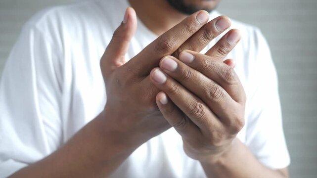 Man massaging painful hand experiencing joint discomfort and arthritis symptoms