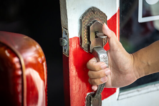 Close-up of a hand opening a vintage door handle at the entrance of a barbershop.