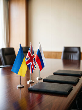 small flags of ukraine united kingdom and russia stand on a table in front of document folders symbolizing complex negotiations international relations and diplomacy