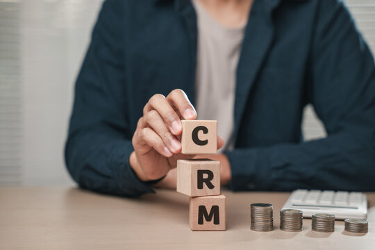 Close up businessman hand holding wooden cube blocks spelling CSR near coins and a calculator. Represents Corporate Social Responsibility, planning, employee performance tracking