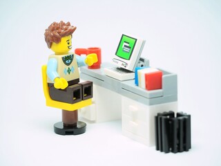 Obraz premium Indonesia - December 24, 2024 : Mini toy of action figure at table with blurred background. Miniature photography concept design. Minifigure of employee character at office desk with smartphone.