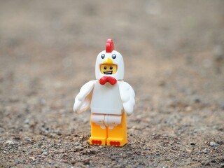 Obraz premium Indonesia - November 23, 2024 : Mini toy of action figure at outdoor with blurred background. Miniature photography concept design. Minifigure of chicken character at rock.