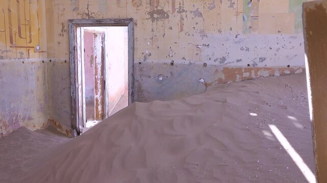 Desert sand dunes filling abandoned interior room of derelict house in Namibia ghost town kolmanskop cinematic footage.