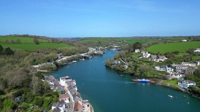 Fowey, Cornwall, England: DRONE VIEWS: The outskirts of the town of Fowey showing the Fowey-Bodinnick ferry reaching the Bodinnick side of the river. Fowey is a popular UK holiday destination.