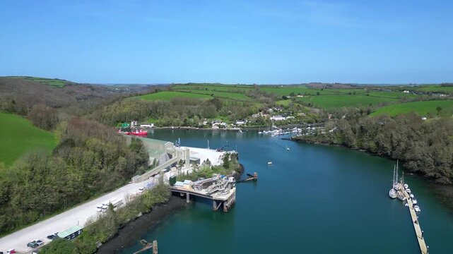 Fowey, Cornwall, England: DRONE VIEWS: Fowey Harbour on the River Fowey; a dock loader prepares a heap of china clay. Fowey docks is a crucial hub for the local mining industry to export clay abroad.