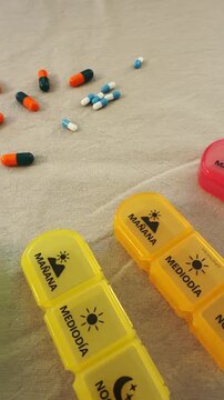 Several pill containers are shown on a table with different colored sections. Pills are sorted inside the boxes for the week. This process shows a method for managing medications.