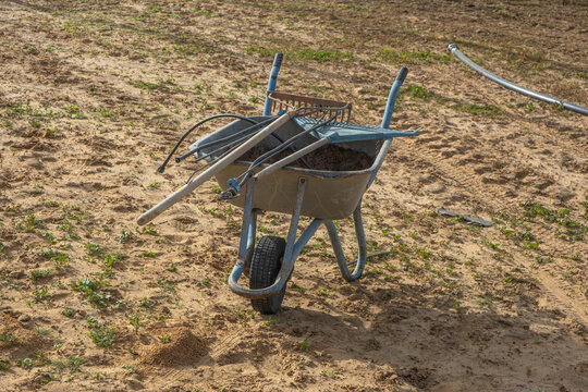 Country background with wheelbarrow and garden tools.