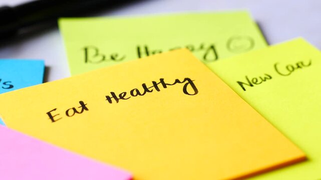 Sticky notes with motivational resolutions and goals on desk with camera motion showing eat healthy and be happy text