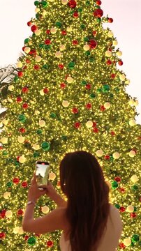 Woman photographing giant decorated Christmas tree in West Palm Beach