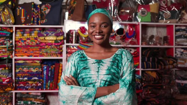 Smiling African woman small business owner operating her vibrant traditional print textiles and accessory business, SME