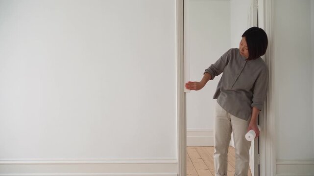 Woman fitting foam weather seal strip along a white door frame at home