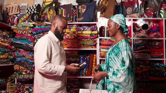African female entrepreneur receiving cash payment from male customer for a shopping in her store